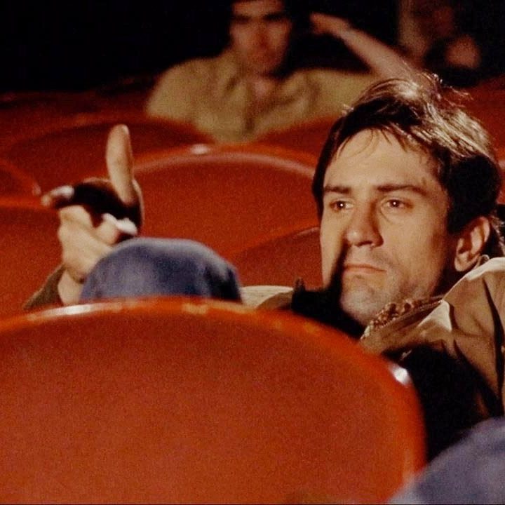 Travis Bickle sits in a theater in Taxi Driver.