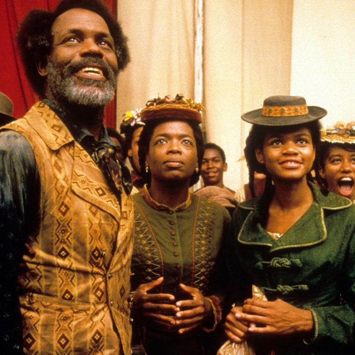 Three people stand next to each other in a crowd in Beloved.