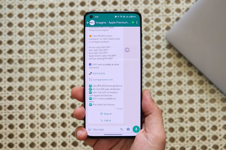 WhatsApp spam message from business on a phone held in hand.