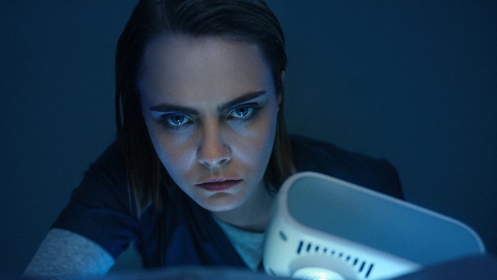 Cara Delevingne looking intensely into the camera with a dark background in a scene from American Horror Story: Delicate.
