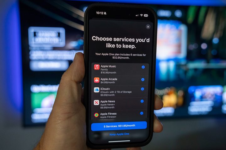 A hand holding an iPhone with the Apple TV+ and other services in a menu.