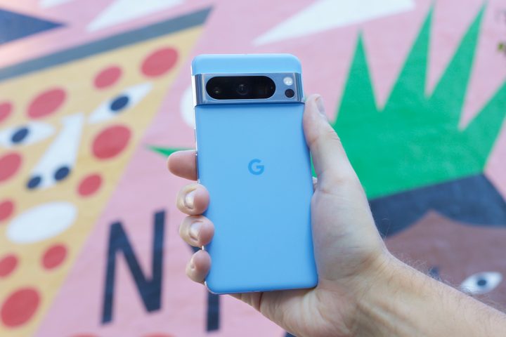Someone holding the Google Pixel 8 Pro in front of a colorful mural.