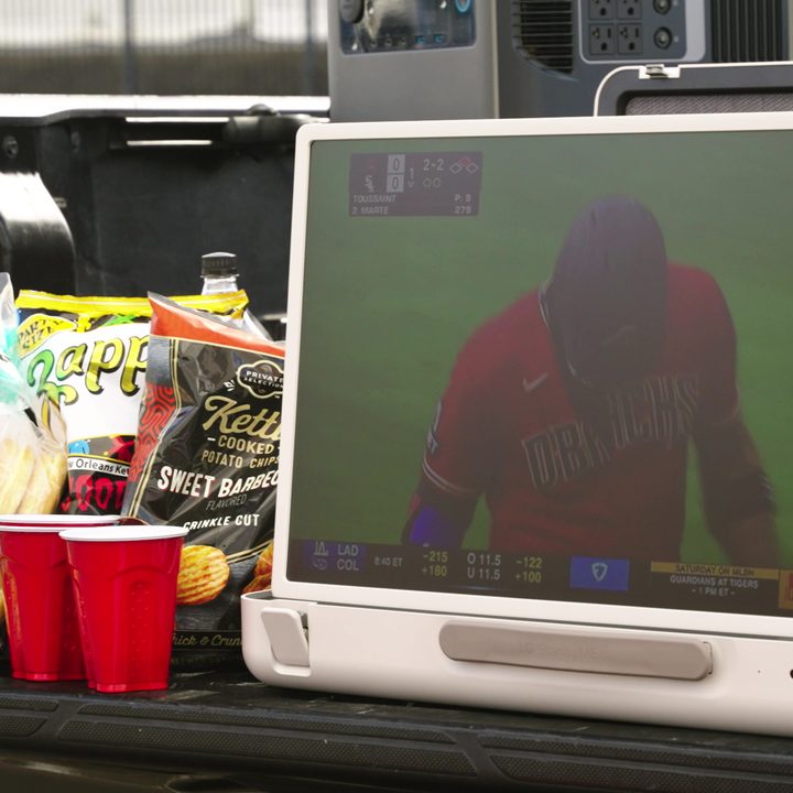 An LG StanbyMe Go briefcase TV showing a baseball game during tailgating.