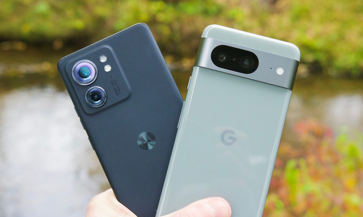 Someone holding the Motorola Edge (2023) next to the Google Pixel 8.