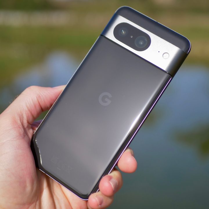 A person holding the Google Pixel 8, showing the back of the phone.