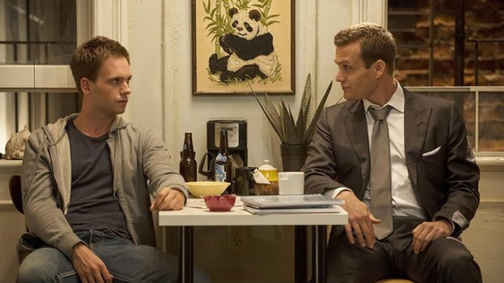 Mike and Harvey sitting across from one another at a small table in a scene from Suits.