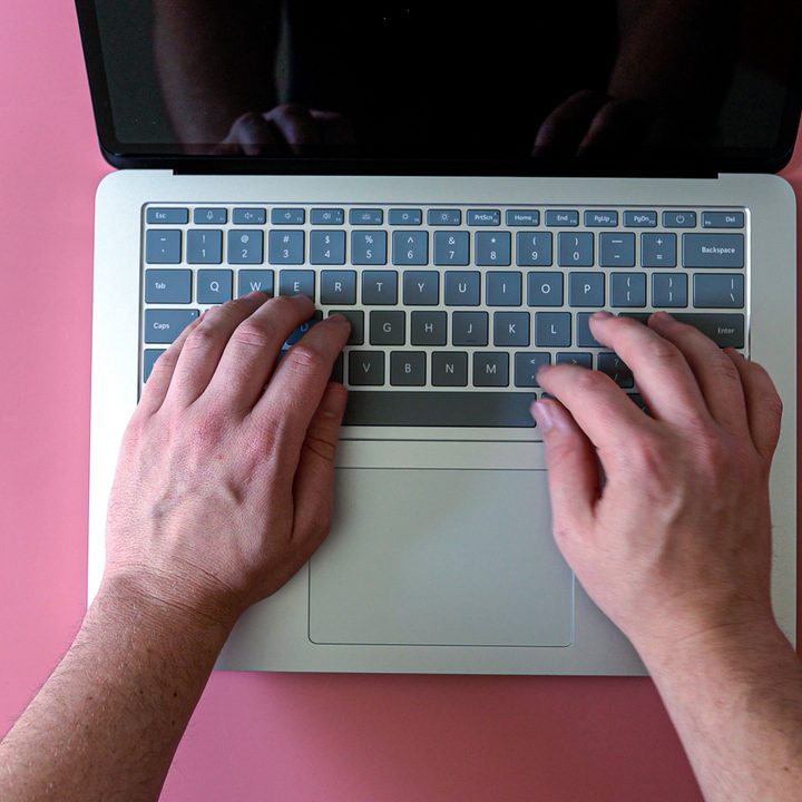 Overhead view of someone typing on a surface laptop.