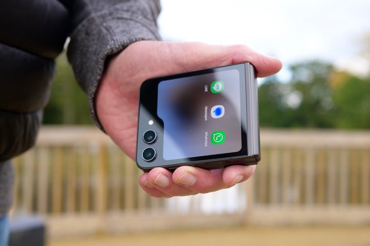 A person holding the Samsung Galaxy Z Flip 5, showing the cover screen.