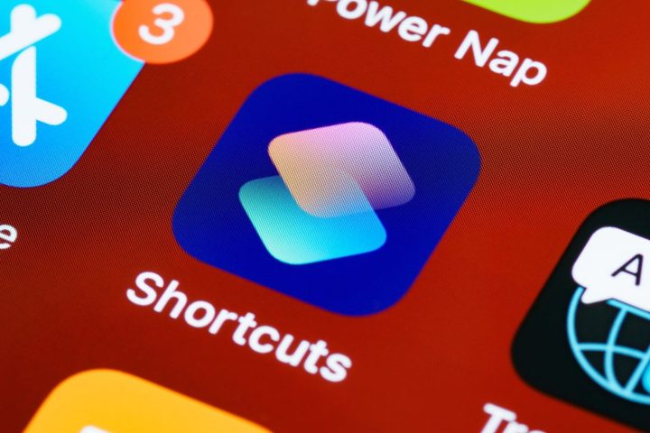 A close-up photo of the Shortcuts app on an Apple device, against a red background.