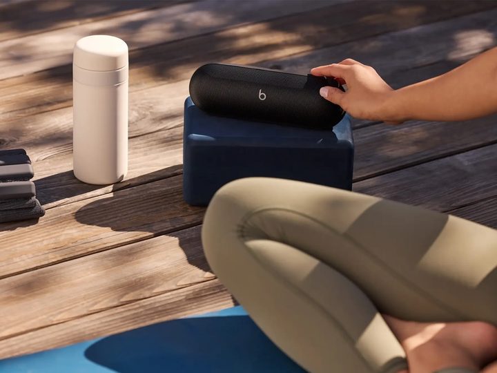 A Beats Pill Bluetooth speaker next to a woman on a yoga mat.