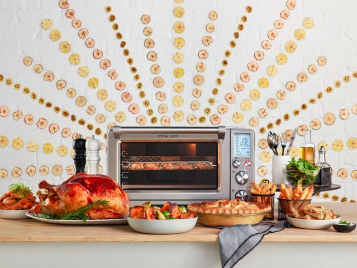 The Breville Smart Oven air fryer and convection toaster on a countertop with a fully prepared Thanksgiving meal.