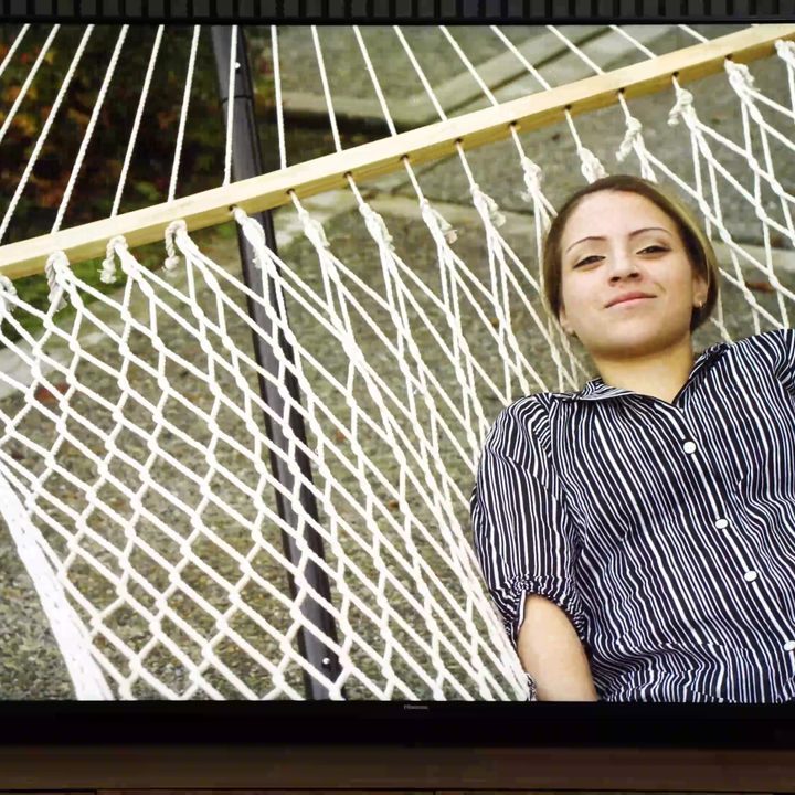A woman lies in a hammock on a Hisense UX TV.