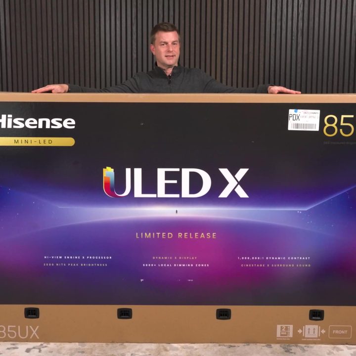 A man stands behind the huge box for a Hisense UX 85-inch TV.