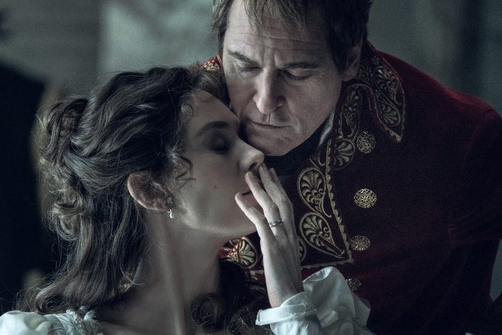 Joaquin Phoenix stands behind Vanessa Kirby in Napoleon.