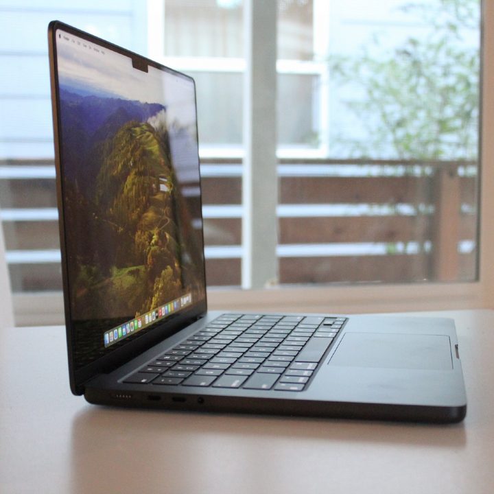 A MacBook Pro on a table in front of a window.
