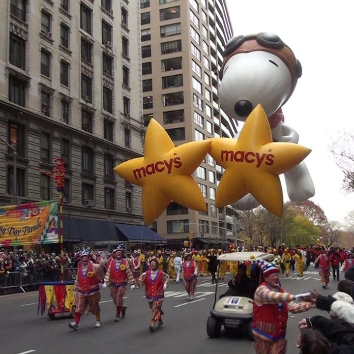 People walk down the street giant parade balloons in New York City.