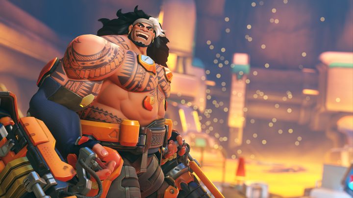 Mauga, a large Samoan man with tattoos on his shoulders and chest, smiles in Overwatch 2.