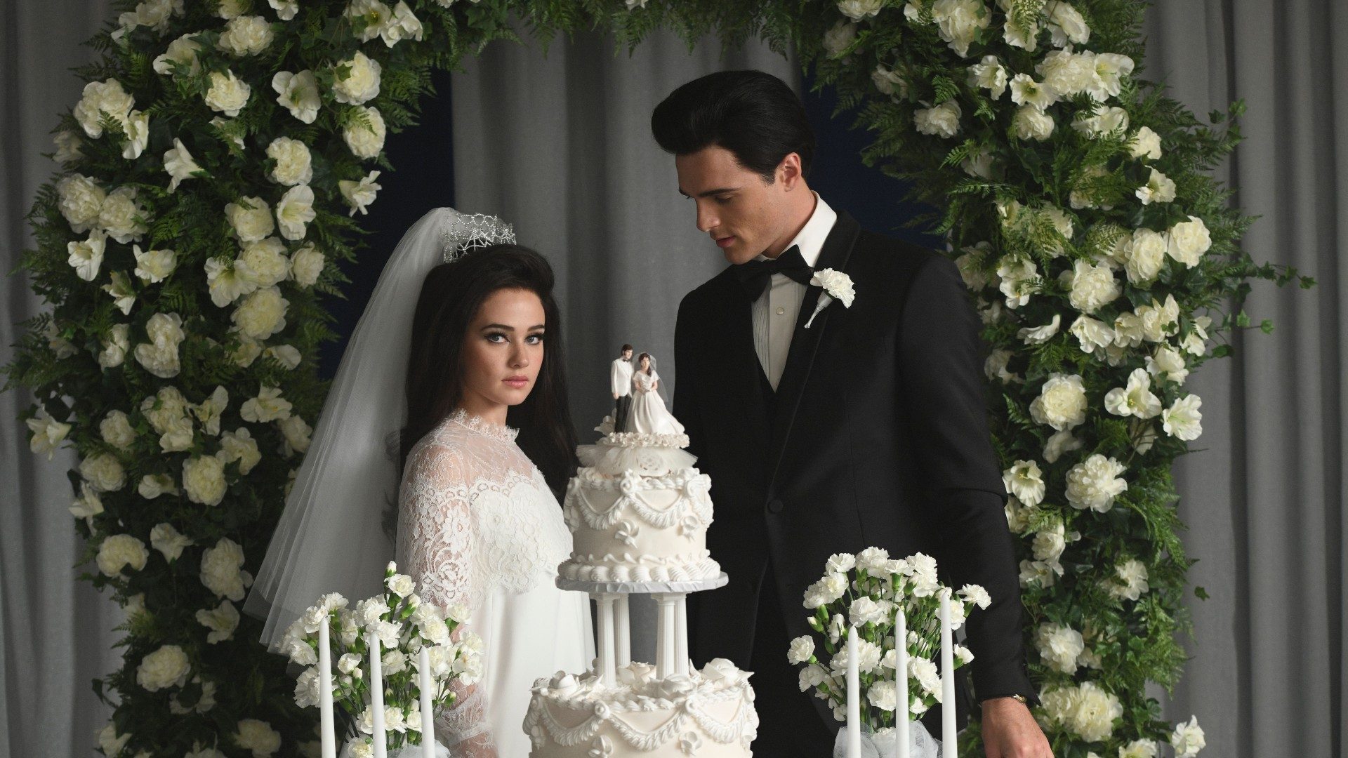 Cailee Spaeny and Jacob Elordi pose for a wedding photo by a cake.