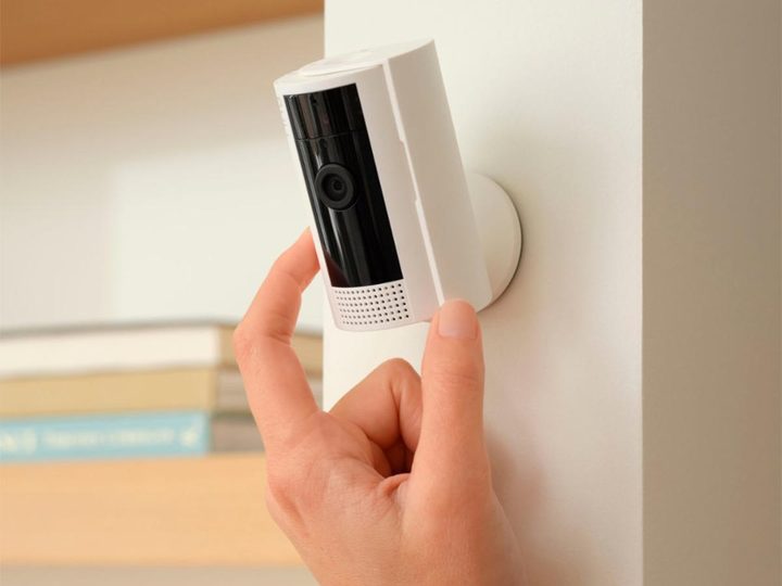 A hand adjusts a Ring Indoor Security Camera mounted on a wall.
