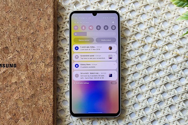 Samsung One UI 6 Notifications on Galaxy A34 kept alongside a notebook on table with retan surface.