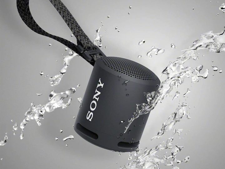 The Sony SRSXB13/B being splashed with water against a gray background.