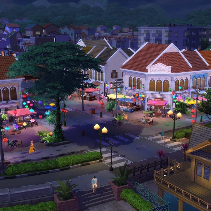 A night market lit up by colorful lights features a number of vending stalls.
