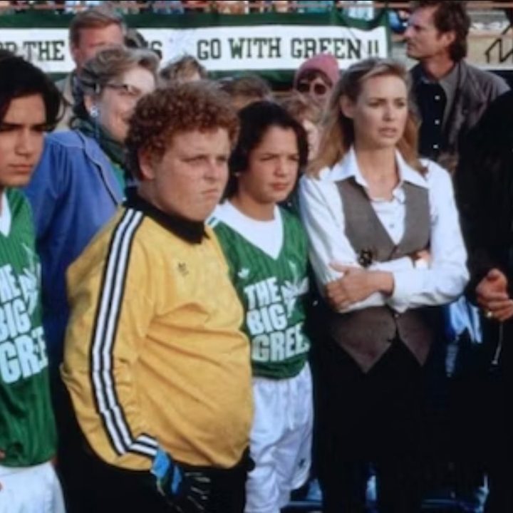 A group of soccer players stand next to their coaches in The Big Green.