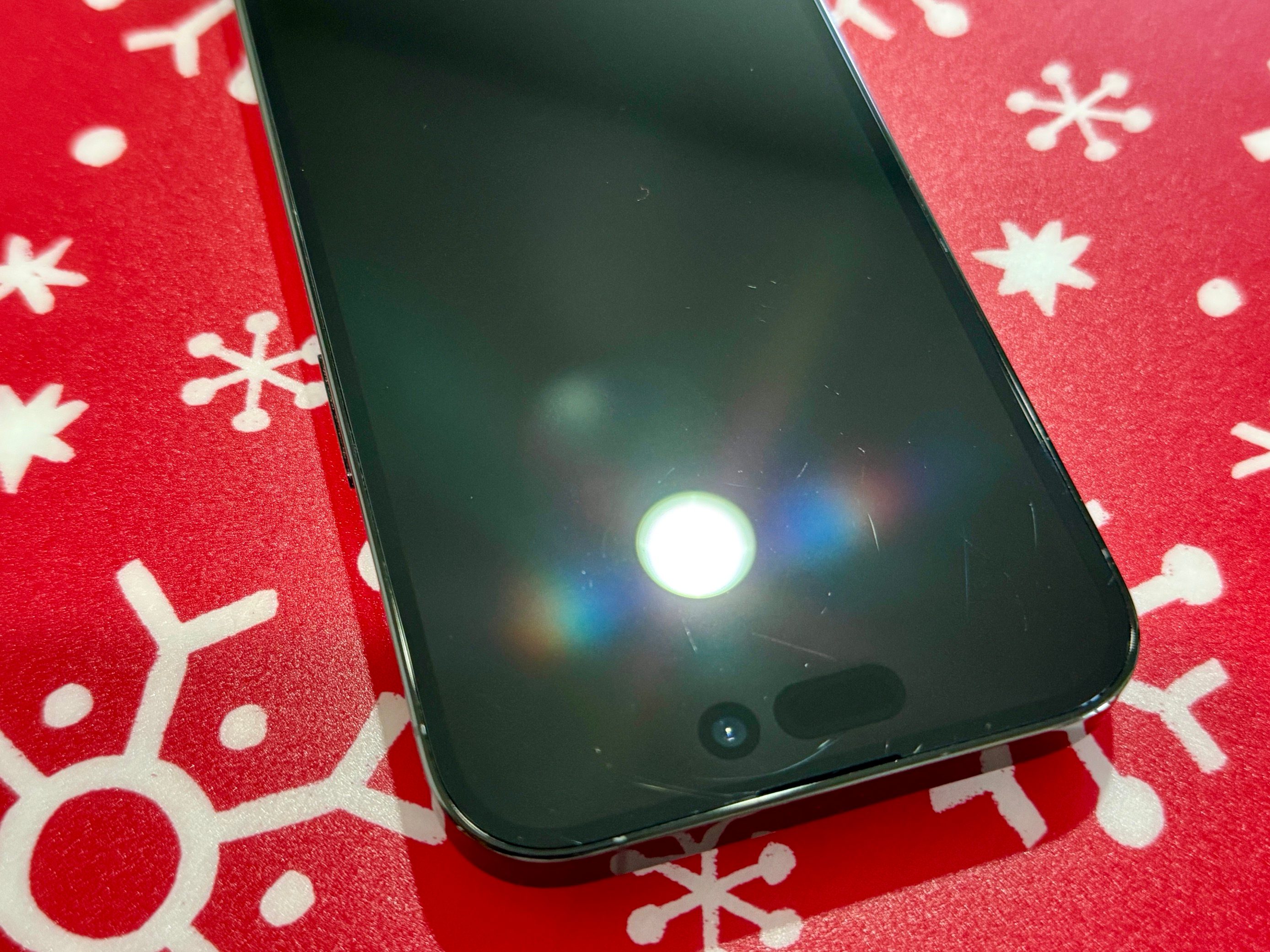 A picture of an iPhone 14 Pro, showing various scratches on its screen.