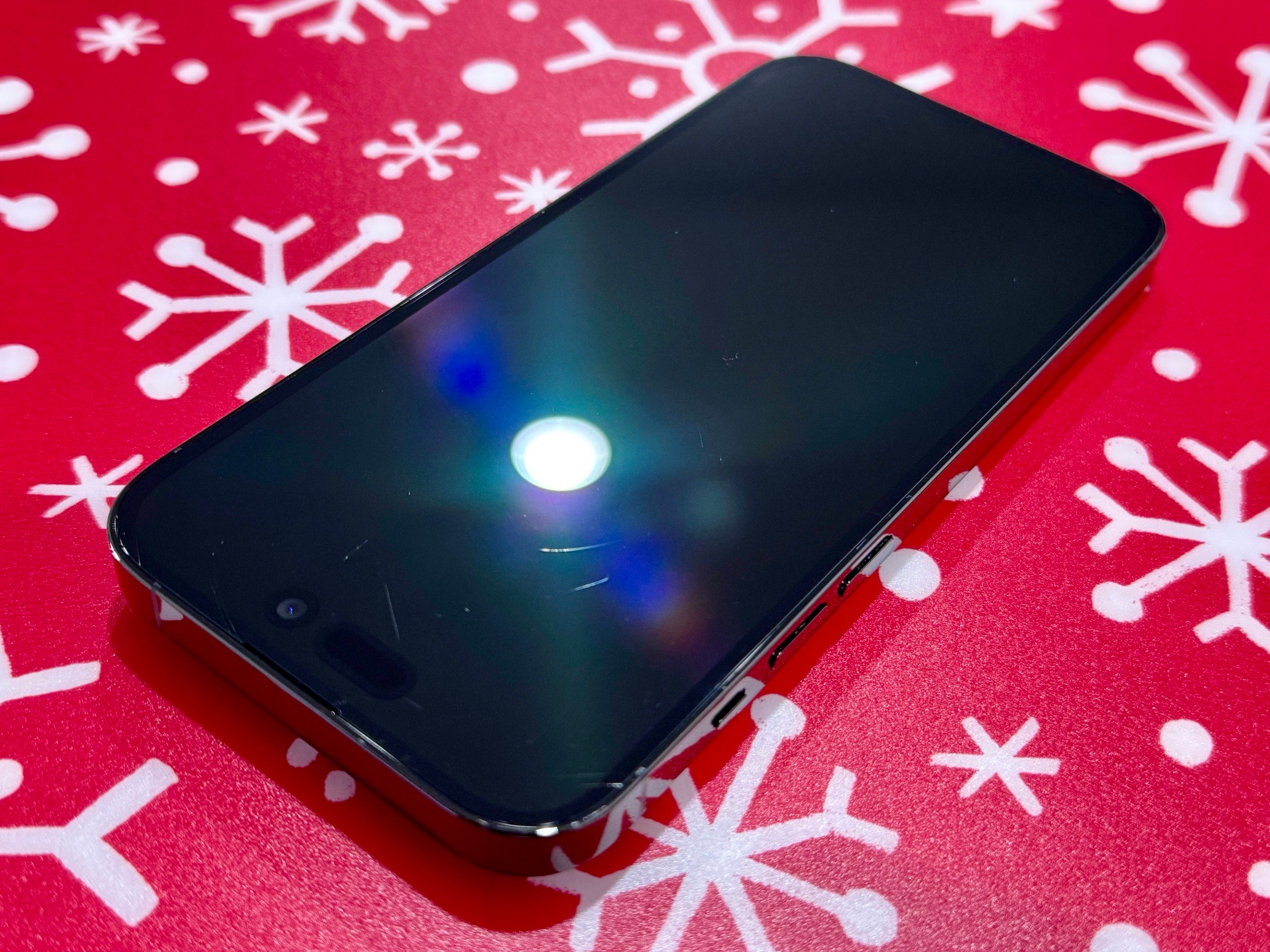 A picture of an iPhone 14 Pro, showing various scratches on its screen.