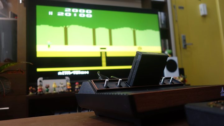 An Atari 2600+ sits on a table running Pitfall.