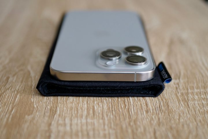 The iPhone 15 Pro Max on top of the Adore June pouch.