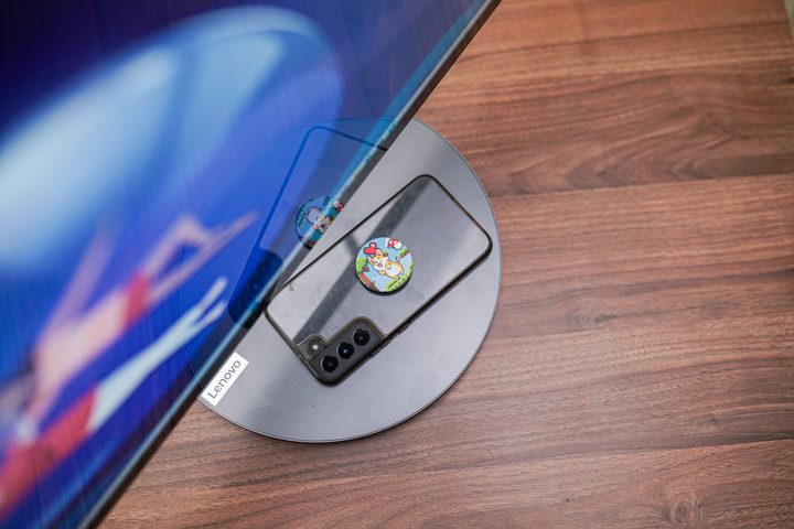 A phone charging on the stand of the Lenovo Yoga AIO 9i.