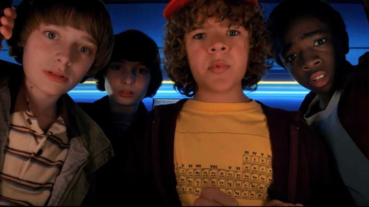 A close up of the kids from Stranger Things looking down at something.