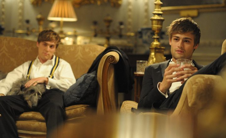 Two men sit on a couch in The Riot Club.