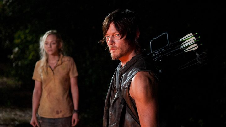 Daryl standing, looking menacing with Beth in the background in a scene from The Walking Dead.