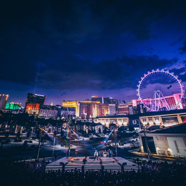 The Las Vegas strip lights up the background inside the Sphere as U2 plays on stage.