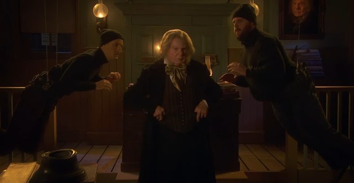 Two men trying to kidnap an actor playing Ebenezer Scrooge in "A Christmas Carol Goes Wrong."
