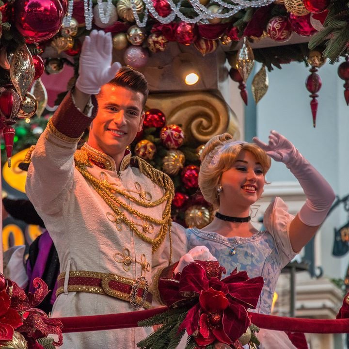 Prince Charming and Cinderella wave on top of a float.