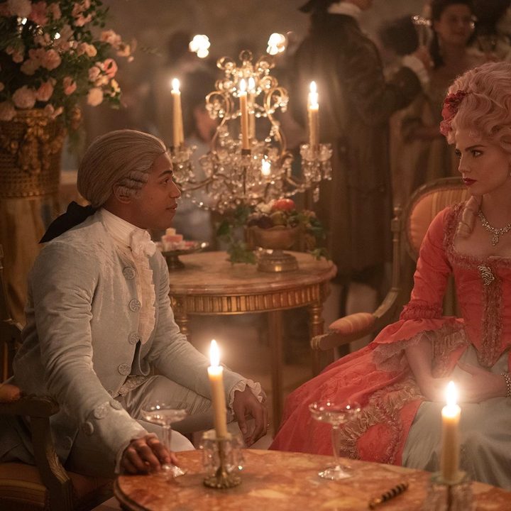 A man and woman have a conversation at a candlelit table.