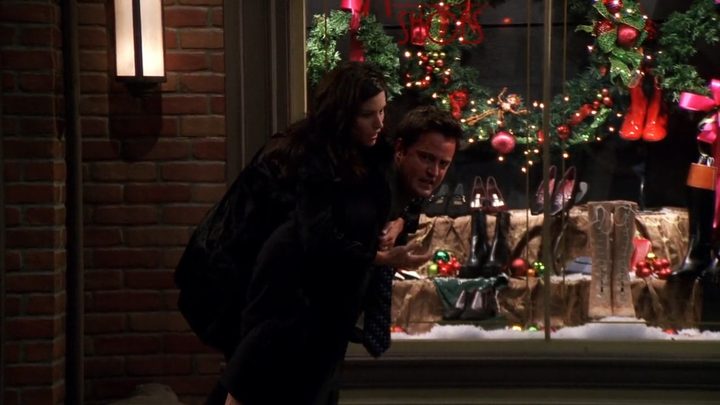 CHandler carrying Monica while walking by a shoe store with Christmas decorations in Friends.