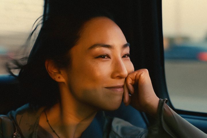 Greta Lee smiles in a car in Past Lives.