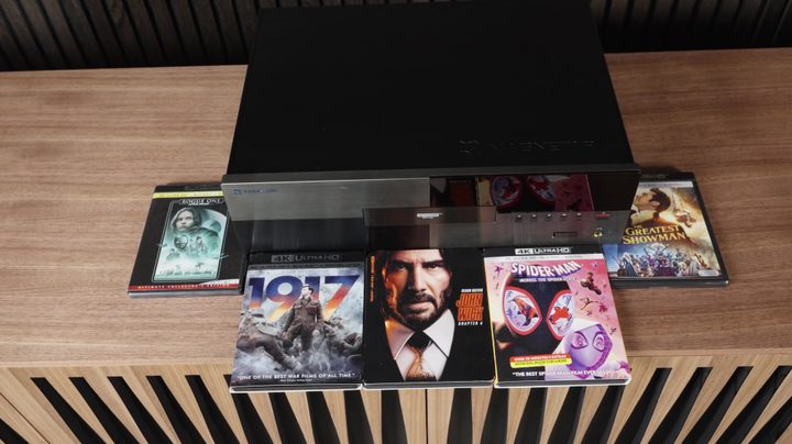 A Magnetar UDP 900 Blu-ray player wiith a selection of Blu-ray discs around it.