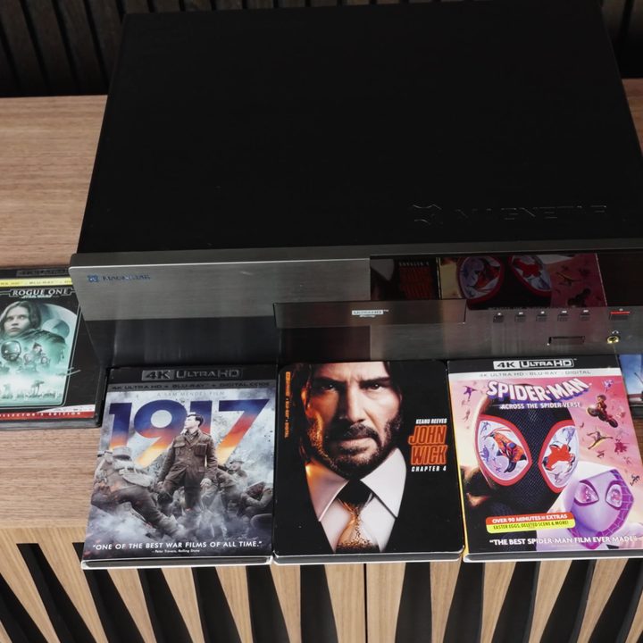A Magnetar UDP 900 Blu-ray player wiith a selection of Blu-ray discs around it.
