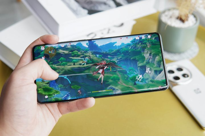 Genshin Impact gaming on OnePlus 12 held in hand.