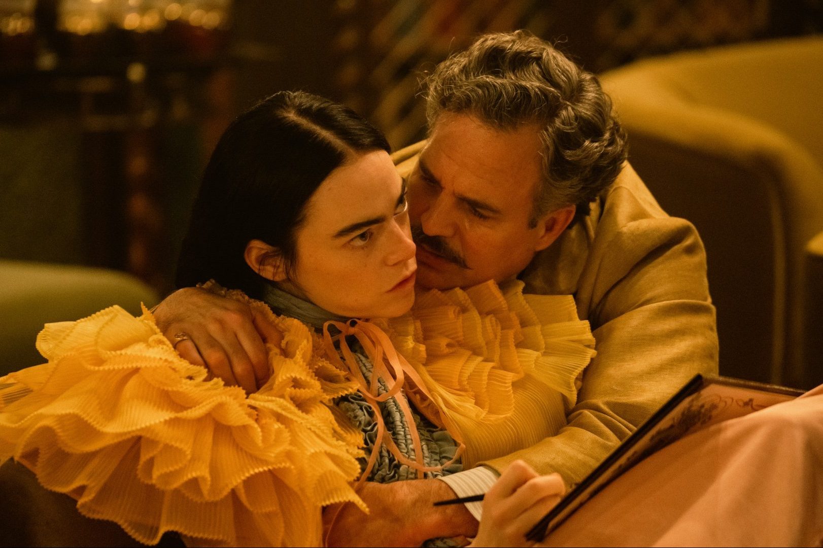 Mark Ruffalo cuddles an indifferent-looking Emma Stone in a still from Poor Things.