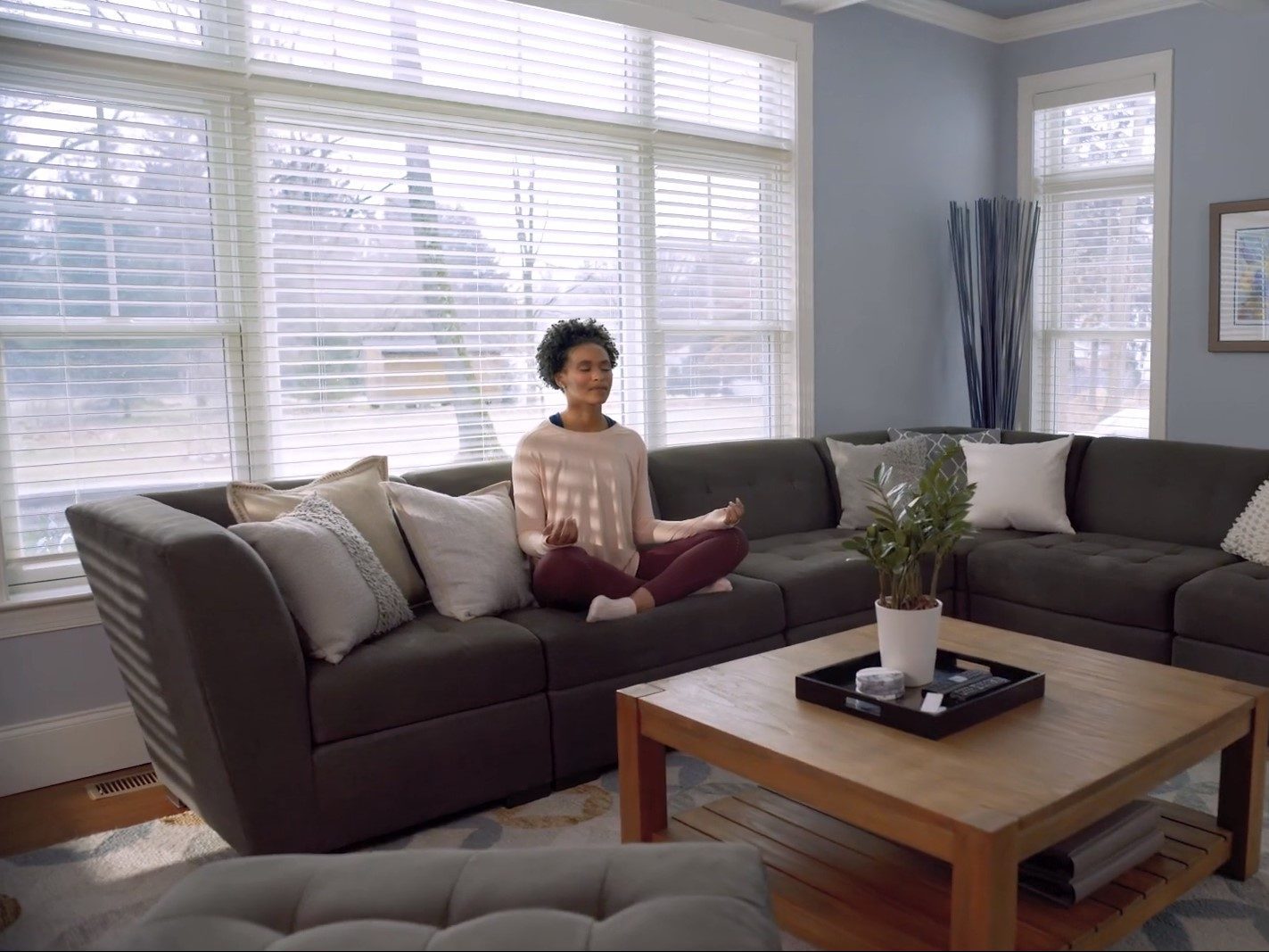 A woman meditating in a room with Serena by Lutron smart blinds / smart shades.