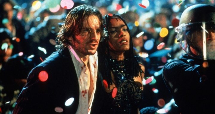 Two people walk in an outdoor party in Strange Days.