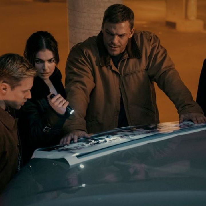 Shaun Sipos, Serinda Swan, Alan Ritchson, and Maria Sten as O'Donnell, Dixon, Reacher, and Neagley looking at a photo spread over a car hood in Reacher season 2.