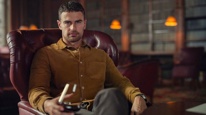 Theo Hames as Eddie Halstead holding a glass and looking at the camera in The Gentlemen.