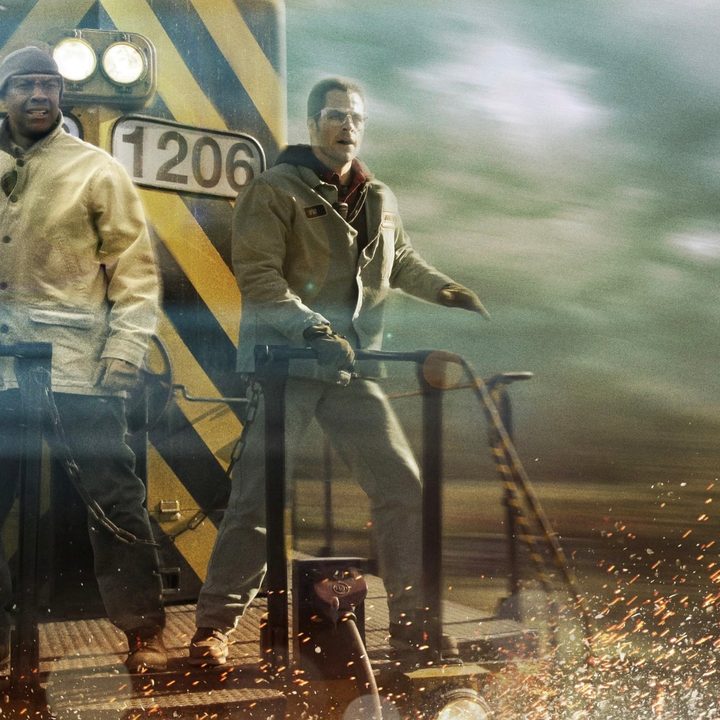 Two men stand on the back of a train in Unstoppable.